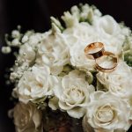 Wedding,Rings,On,The,Wedding,Bouquet,Of,White,Roses.